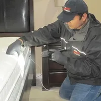 Bed bug inspection technician checking a mattress and bed frame for signs of infestation in Anchorage, AK