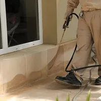 General pest control technician spraying exterior perimeter around a home in Anchorage, AK
